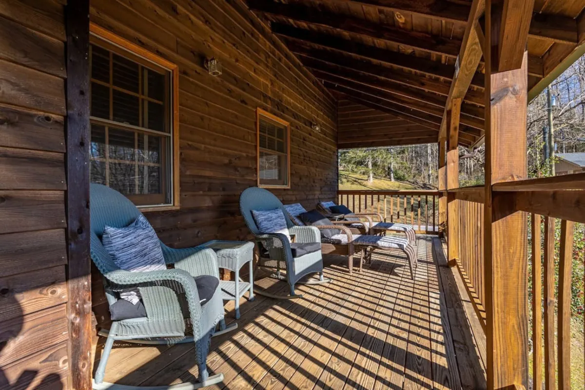 The image features a tranquil exterior deck area with classic wooden rocking chairs, surrounded by serene natural scenery. The open space is perfect for relaxing after an eventful day or enjoying the outdoors with friends.